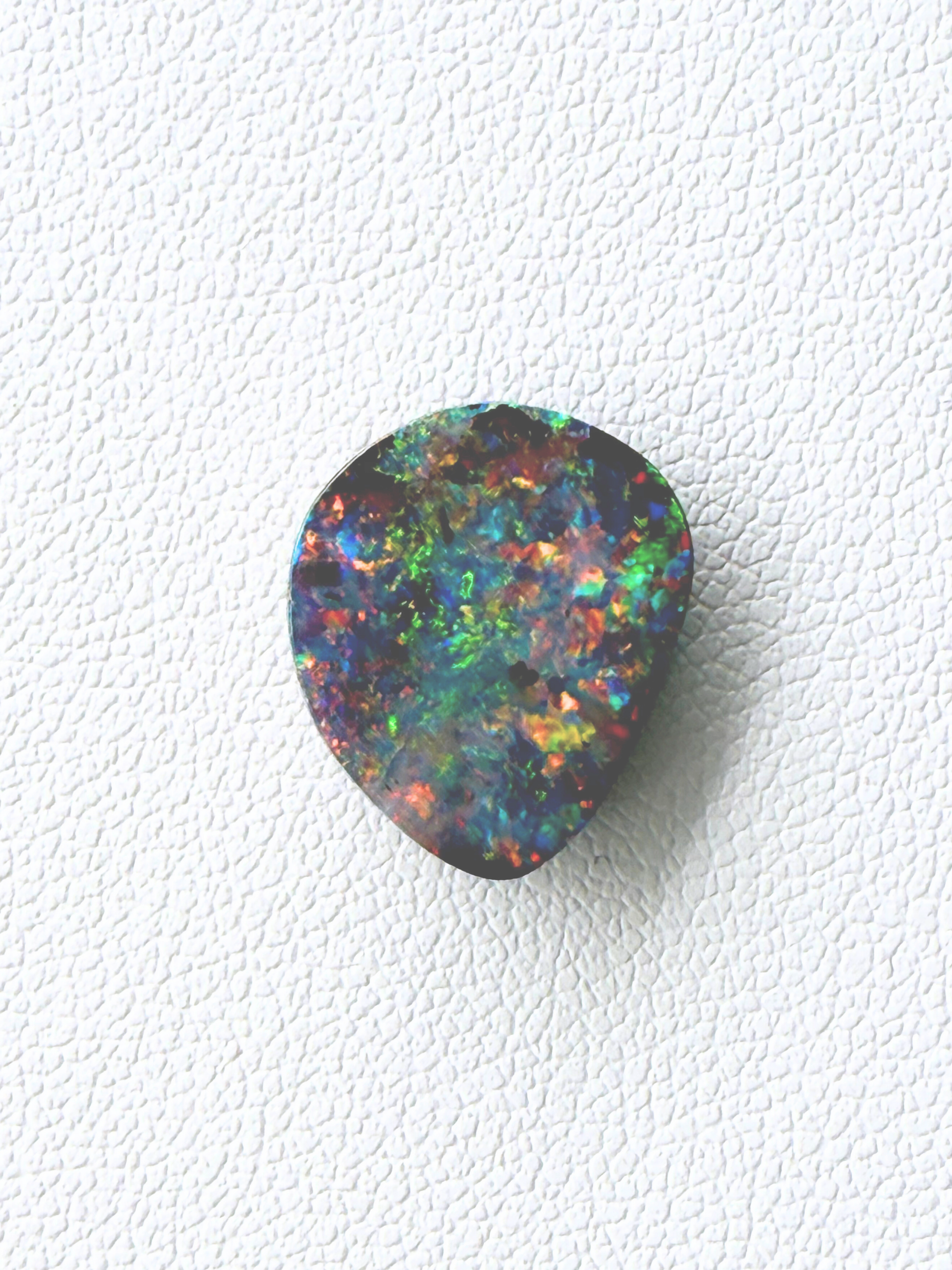 Multicolored opal stone on a white textured background