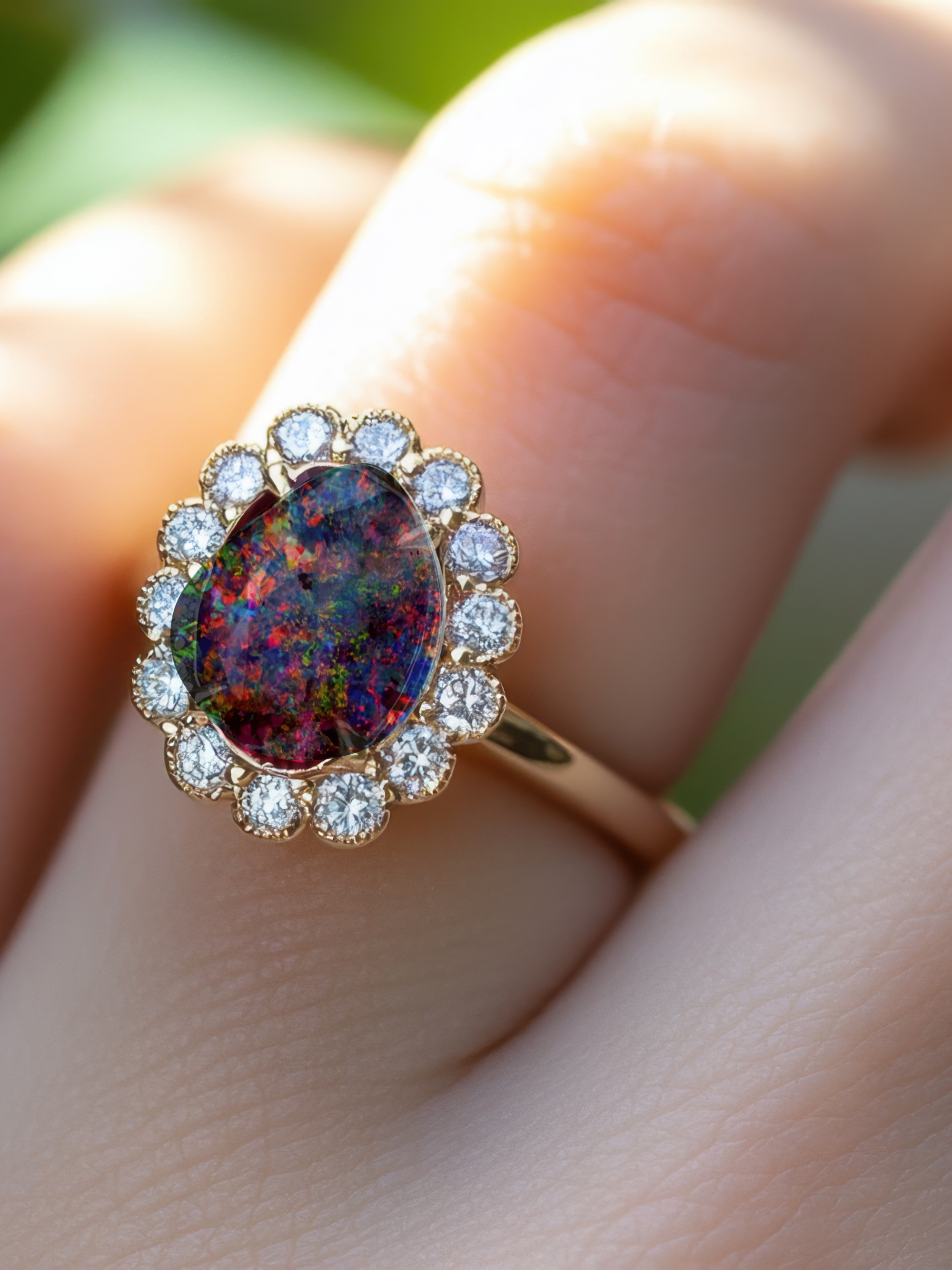 Ring with a colorful gemstone and diamond accents on a finger