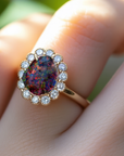 Ring with a colorful gemstone and diamond accents on a finger